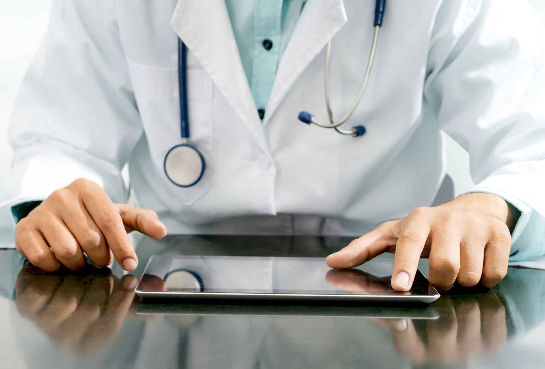 Profesional médico con bata blanca usando una tablet para revisar contenidos IA SGE médicos y mejorar la visibilidad online de su clínica